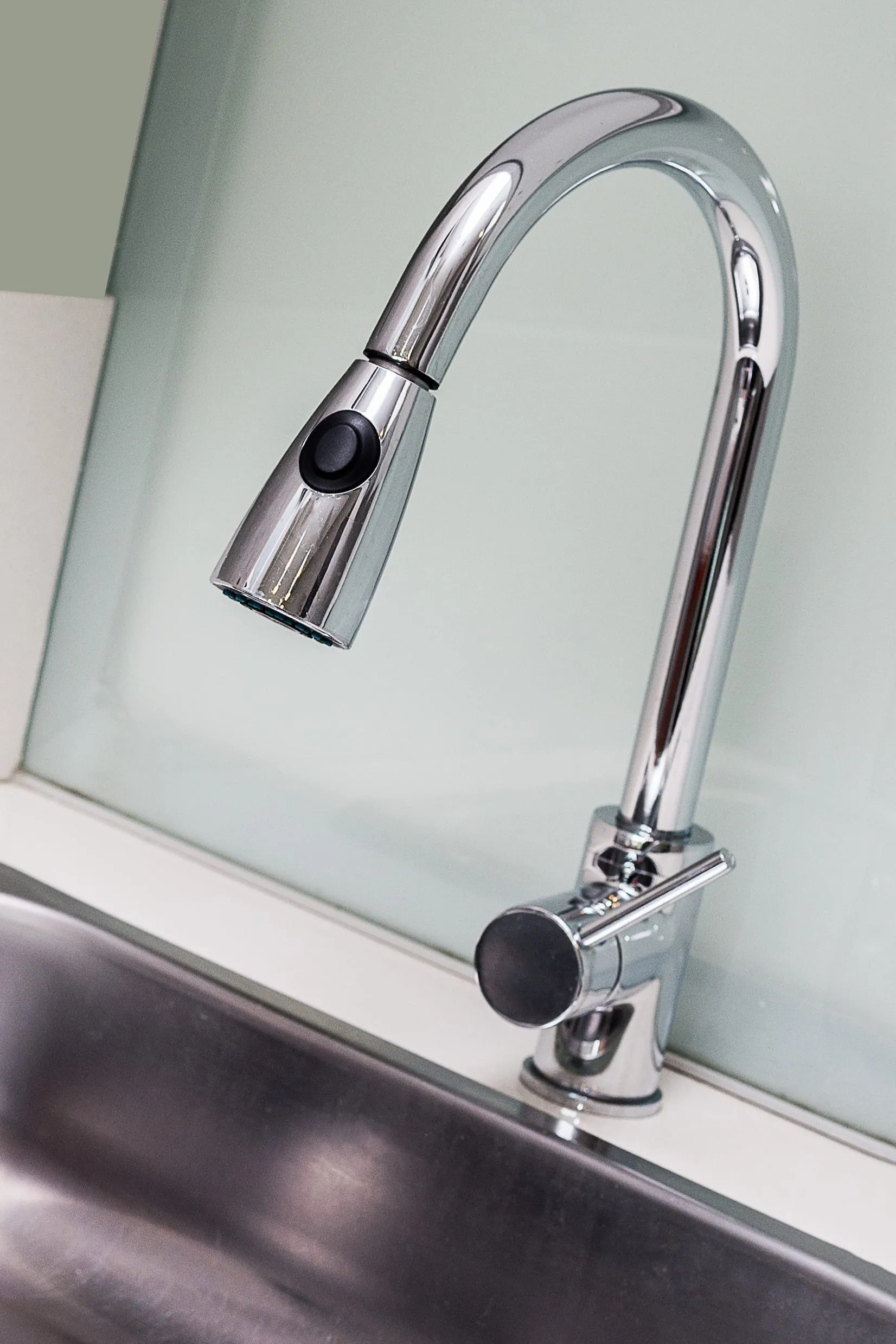 A chrome pull-down mixer tap over a white sink